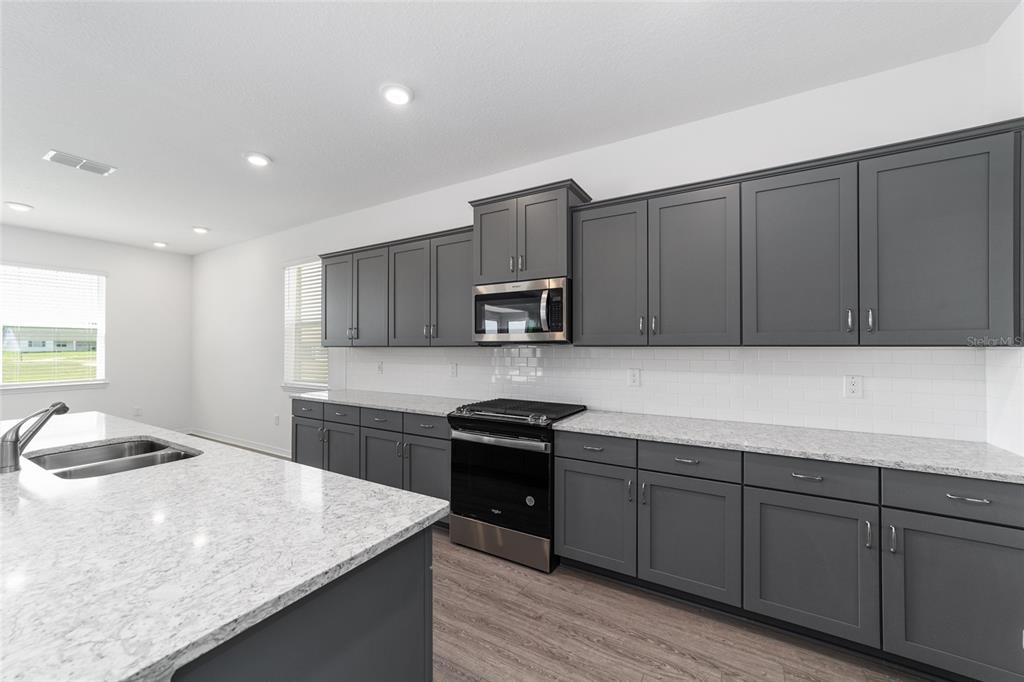 7232 Southwest 63rd Street Ocala, FL 34474 - Photo 23 of 54 a kitchen with kitchen island granite countertop a sink and wooden cabinets