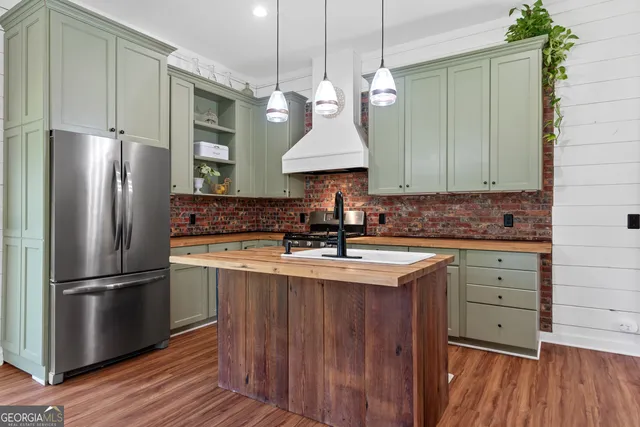 a kitchen with kitchen island granite countertop a stove a refrigerator and a wooden floors