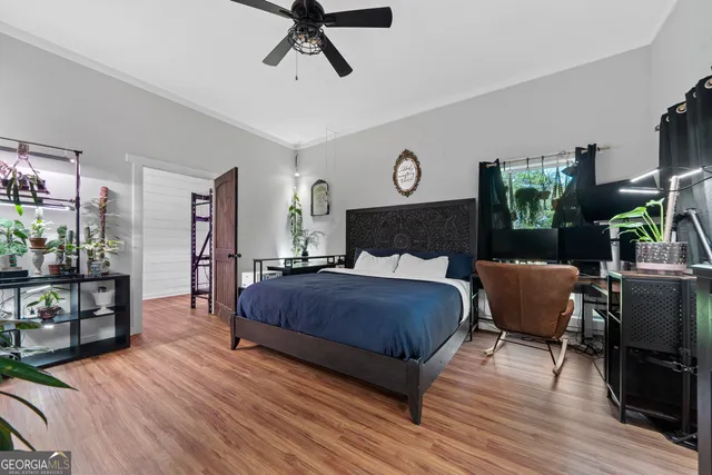 a bedroom with a bed a mirror on dresser and a wooden floor