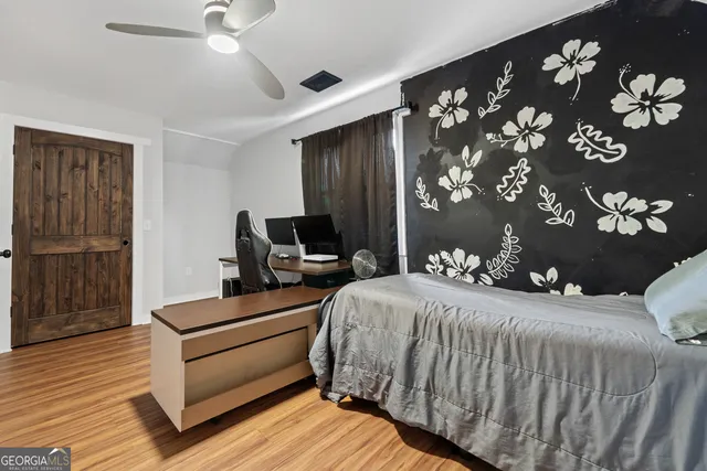 a bedroom with a bed dresser and wooden floor