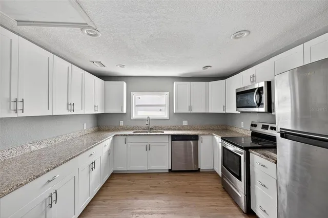 an aerial view of a house with yard and trees all around