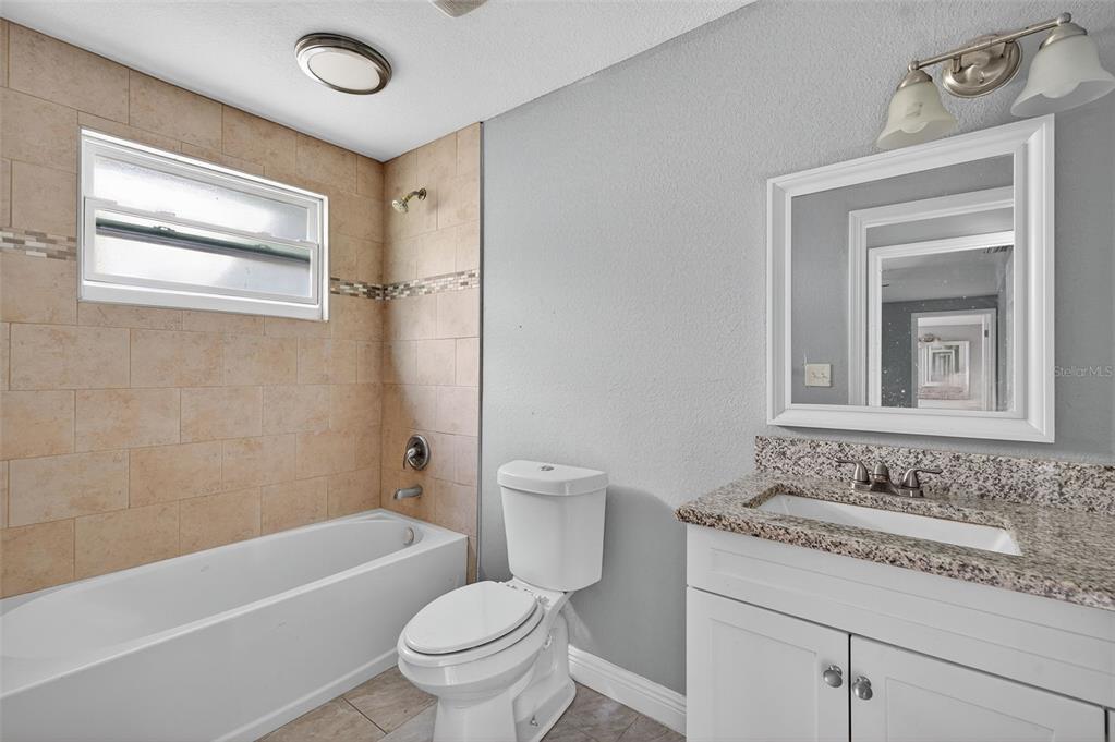 5801 Virginia Avenue New Port Richey, FL 34652 - Photo 31 of 81 a bathroom with a granite countertop sink toilet and shower