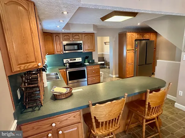a kitchen with stainless steel appliances kitchen island granite countertop a table chairs in it and wooden floors