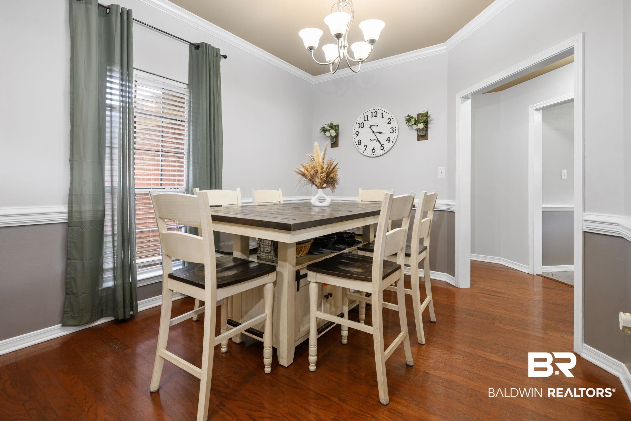 9422 Labrador Run South Mobile, AL 36695 - Photo 11 of 36 Dining area featuring rich wood-finish flooring, a contemporary chandelier, two-tone wall paneling, crown molding, and a large window with blinds