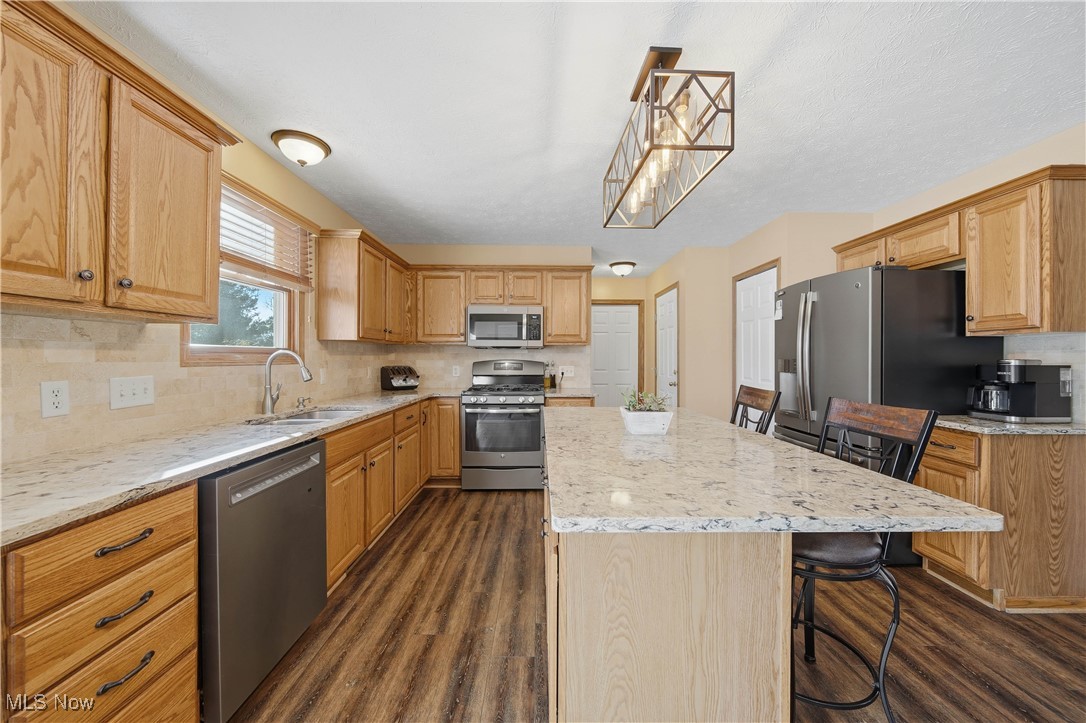 2132 Summerchase Road Northeast Canton, OH 44721 - Photo 9 of 49 Kitchen featuring a kitchen breakfast bar, appliances with stainless steel finishes, a center island, light stone counters, and decorative backsplash