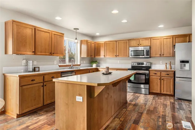 a kitchen with stainless steel appliances granite countertop a sink stove refrigerator and cabinets