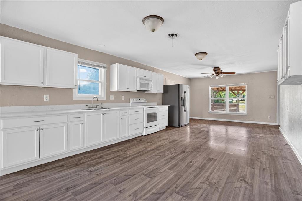 320 North 2nd Street Jacksboro, TX 76458 - Photo 4 of 16 a large kitchen with a hard wood floor stainless steel appliances and window