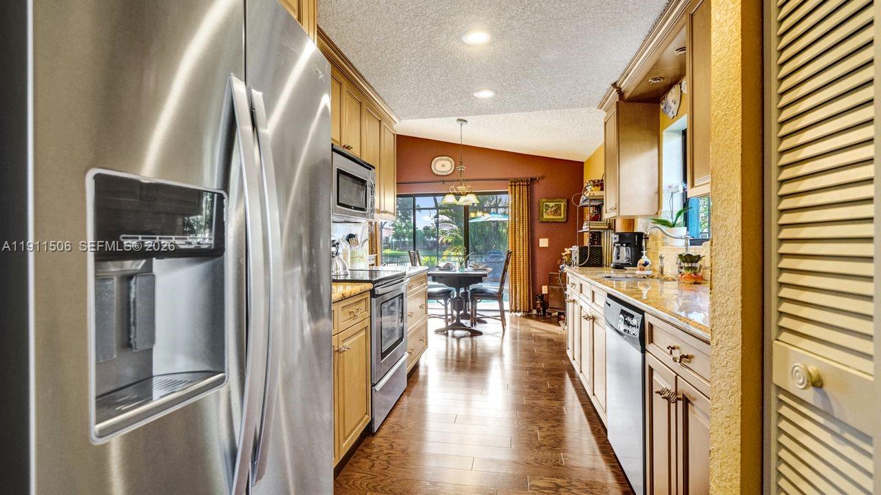 10858 White Aspen Lane Boca Raton, FL 33428 - Photo 12 of 72 a kitchen with stainless steel appliances granite countertop a refrigerator a stove and a wooden floor