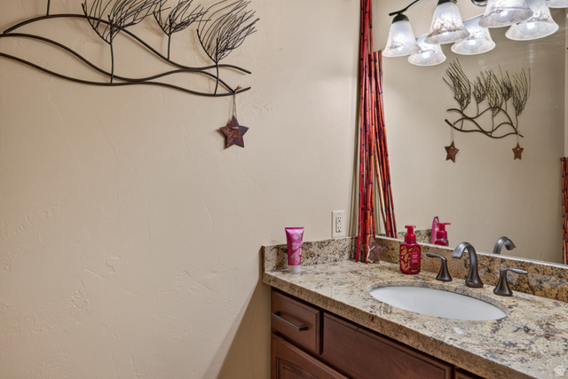 4635 East Sunny Acres Lane Moab, UT 84532 - Photo 33 of 56 Vanity featuring a stone countertop, an undermount sink, and a dark bronze widespread faucet