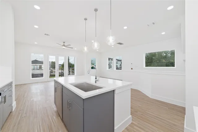 a kitchen with a sink dishwasher and a wooden floor with outer view