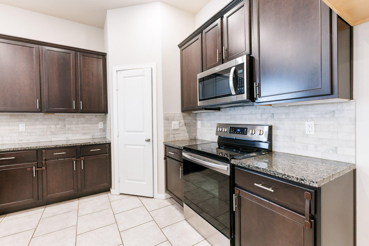 7509 26th Street Lubbock, TX 79407 - Photo 12 of 48 a kitchen with stainless steel appliances granite countertop a stove microwave and refrigerator