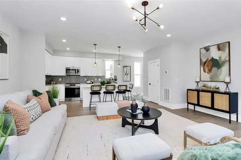 a living room with furniture a rug kitchen view and a chandelier