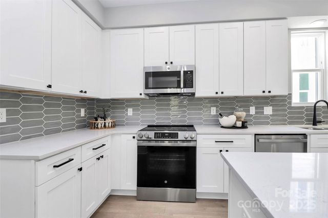 a kitchen with granite countertop white cabinets and stainless steel appliances