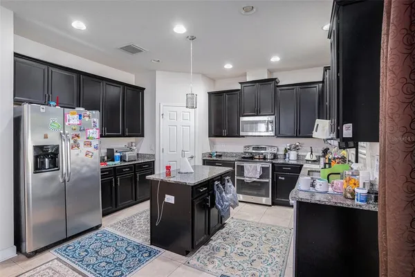 a kitchen with stainless steel appliances kitchen island granite countertop a refrigerator stove microwave and sink