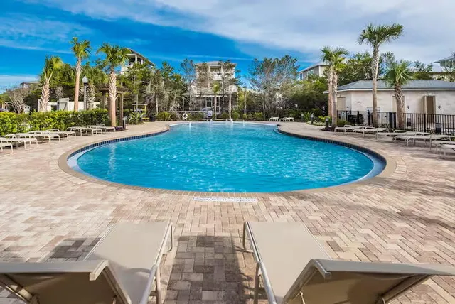 a view of a swimming pool with lawn chairs under an umbrella