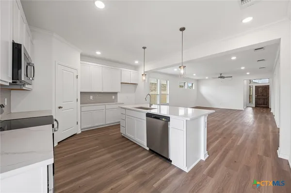 a large kitchen with granite countertop a large counter top stainless steel appliances and wooden floor
