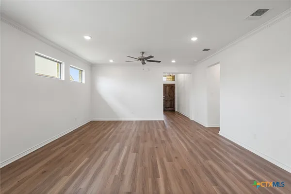 a view of a hallway with wooden floor and a ceiling fan
