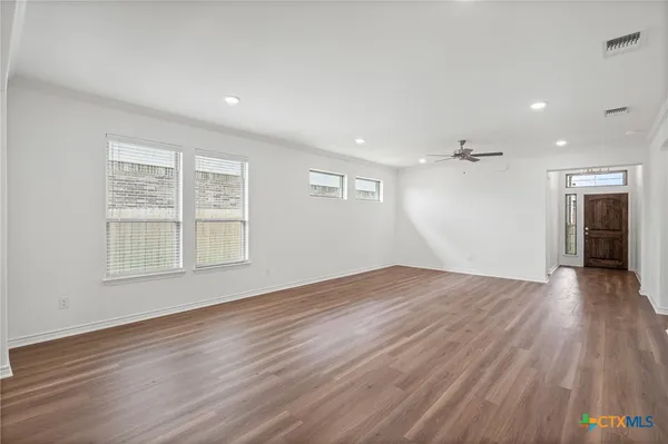 an empty room with wooden floor and windows