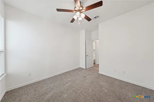 an empty room with a ceiling fan and a window