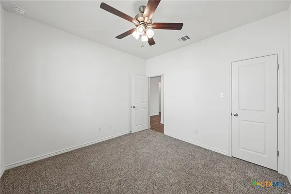 an empty room with a chandelier fan and windows