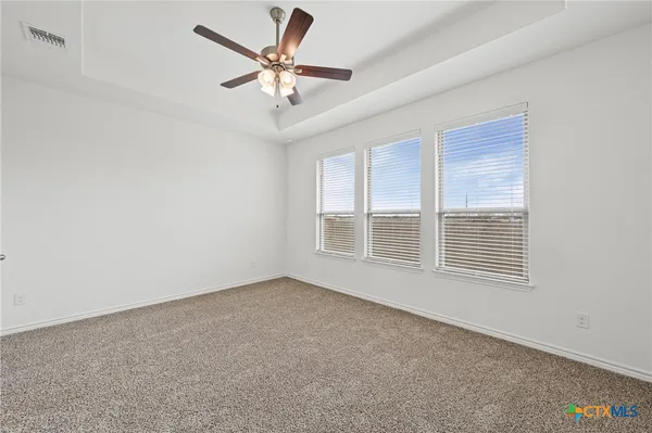 an empty room with chandelier fan and windows