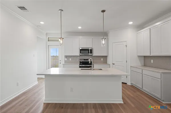 a large kitchen with stainless steel appliances a large counter top a stove a refrigerator and a sink