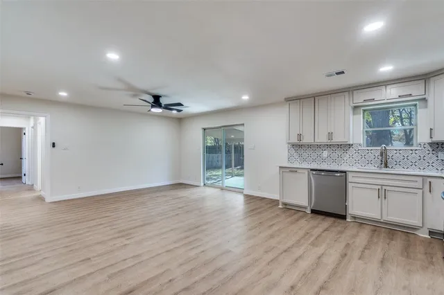 a large kitchen with granite countertop a stove top oven a sink and a granite counter tops with wooden floors