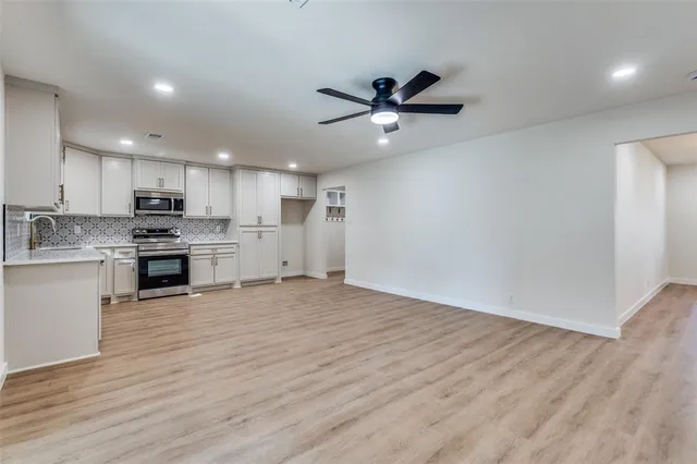 a view of kitchen with kitchen island wooden floors appliances and cabinets
