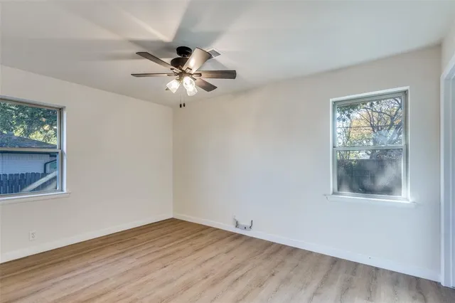 a view of an empty room with a window and a chandelier fan
