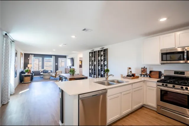 a view of a kitchen with a sink dishwasher stove and wooden cabinets