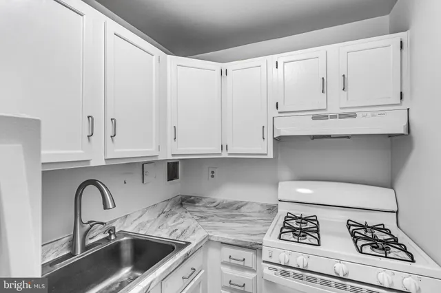 a kitchen with granite countertop white cabinets and white appliances