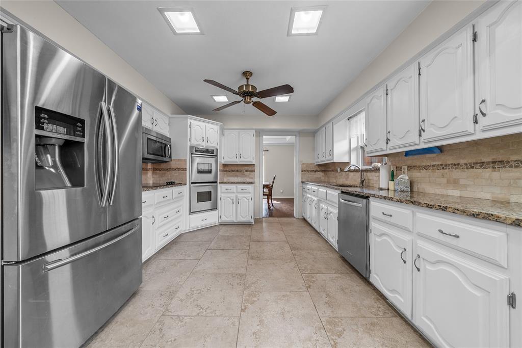 9727 Amberley Drive Dallas, TX 75243 - Photo 4 of 19 a large kitchen with stainless steel appliances granite countertop a refrigerator oven a stove top oven and white cabinets