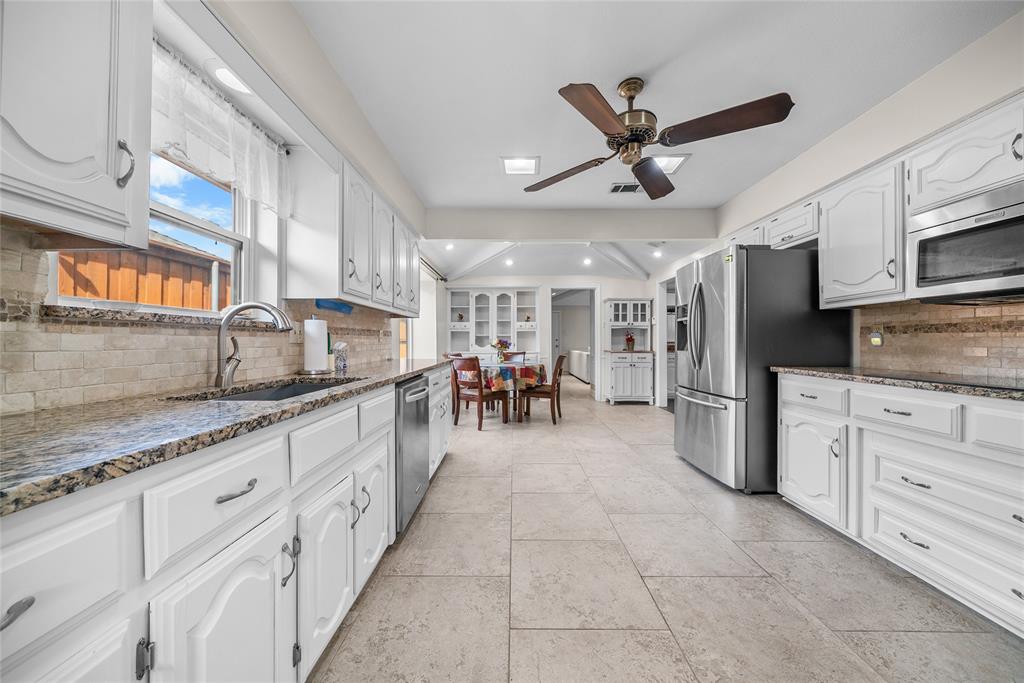 9727 Amberley Drive Dallas, TX 75243 - Photo 7 of 19 a kitchen with white cabinets and stainless steel appliances