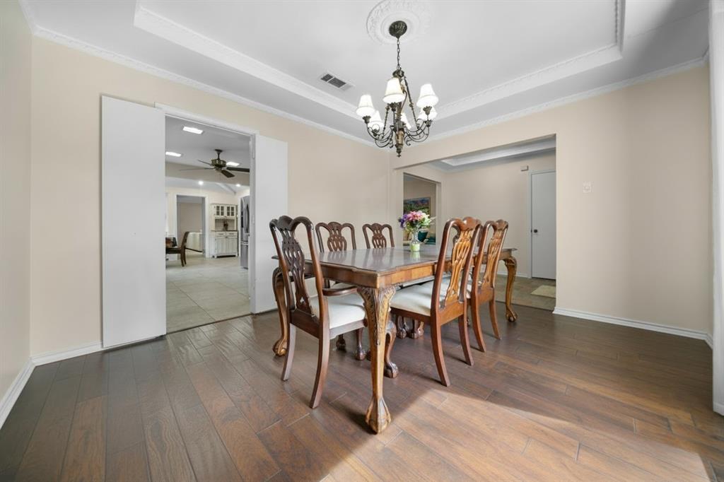 9727 Amberley Drive Dallas, TX 75243 - Photo 8 of 19 a view of a dining room with furniture a chandelier and wooden floor