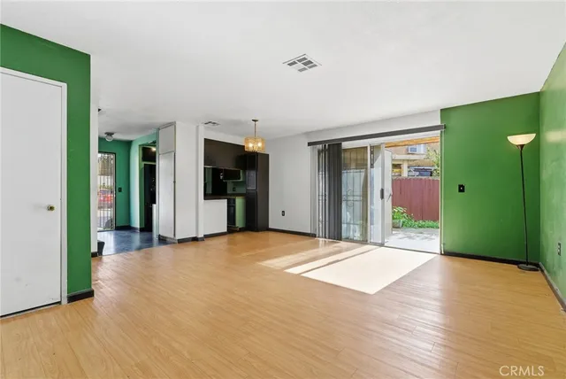 a view of an empty room with kitchen and a window