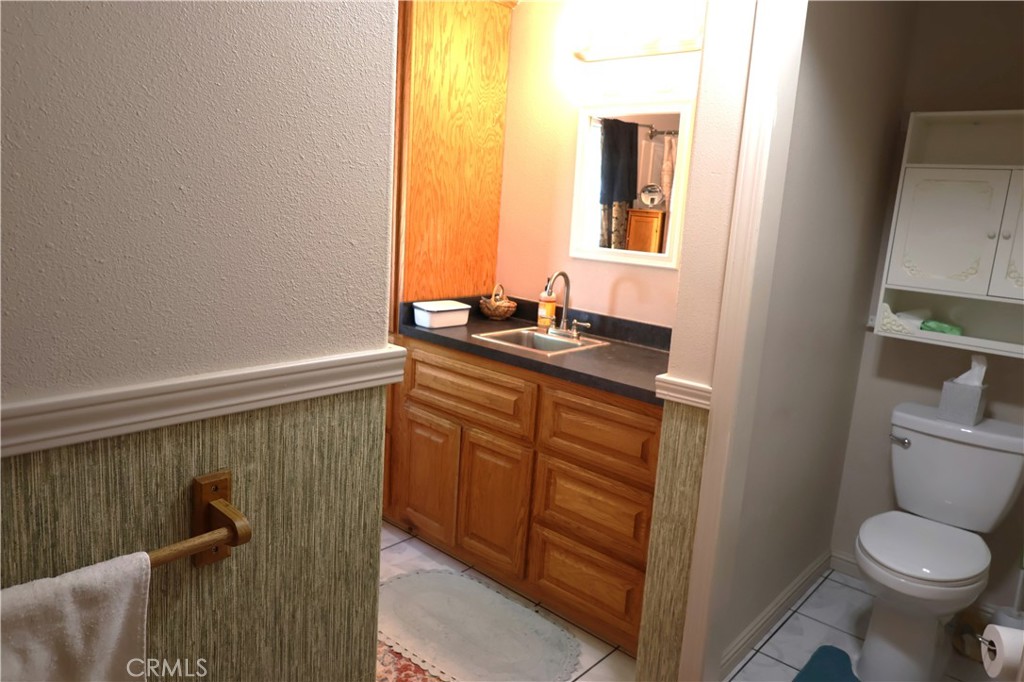 22189 Samson Avenue Corning, CA 96021 - Photo 24 of 59 a bathroom with a granite countertop toilet sink and mirror