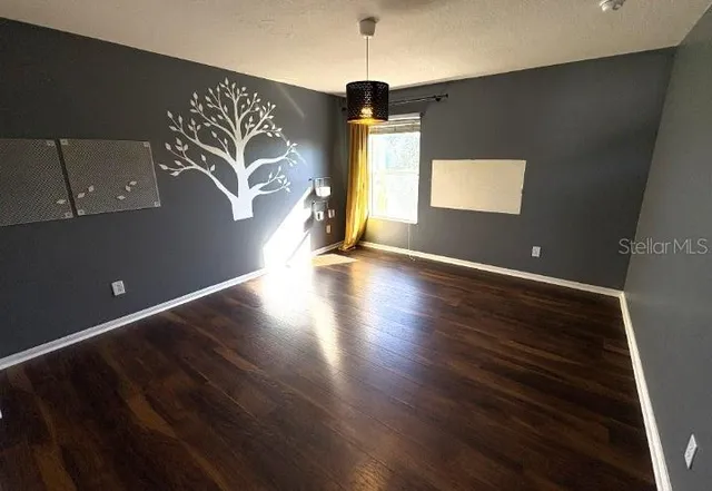 a view of an empty room with window and wooden floor