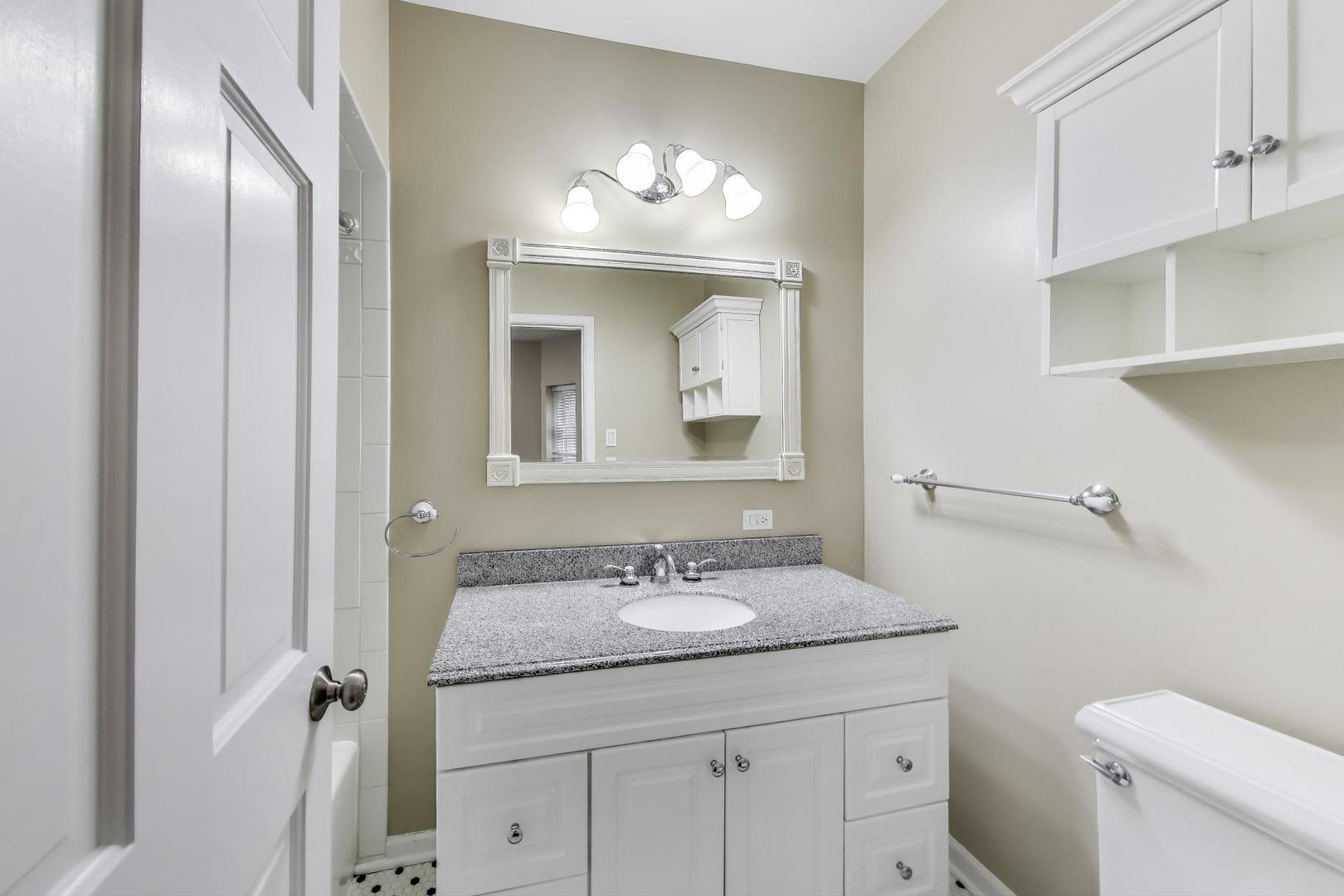 636 West Grace Street, Unit 2W Chicago, IL 60613 - Photo 18 of 26 a bathroom with a granite countertop sink a toilet and a mirror