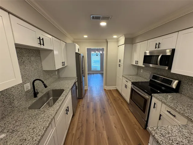 a kitchen with stainless steel appliances a sink a stove top oven a counter space and cabinets