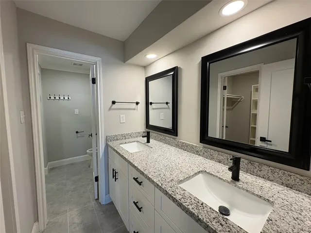 a bathroom with a granite countertop double vanity sink and a mirror