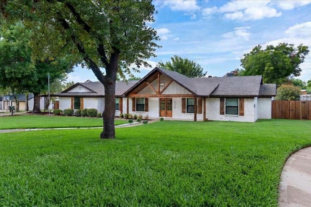 3509 West Sublett Road Arlington, TX 76017 - Photo 3 of 39 White exterior with dark roof shingles, front porch with wood beam accents, wood double entry doors, wood window shutters, and a front yard with established landscaping