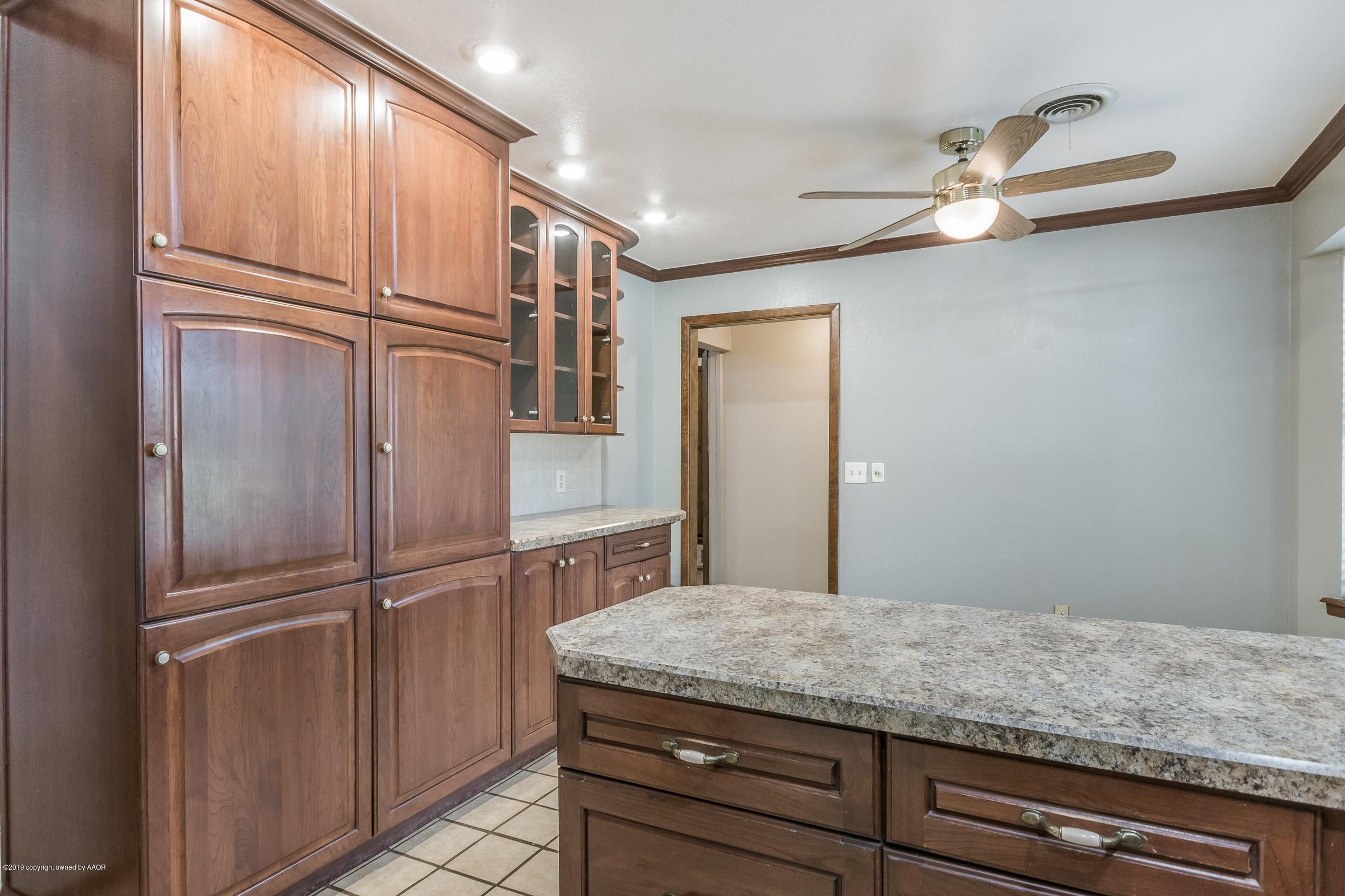 5610 Southwest 41st Avenue Amarillo, TX 79109 - Photo 11 of 30 a room with kitchen island a refrigerator wooden floor and cabinets