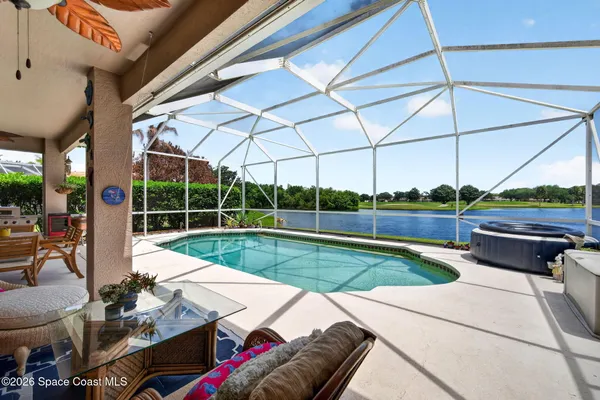 a view of a patio with dining table and chairs under an umbrella with a small yard