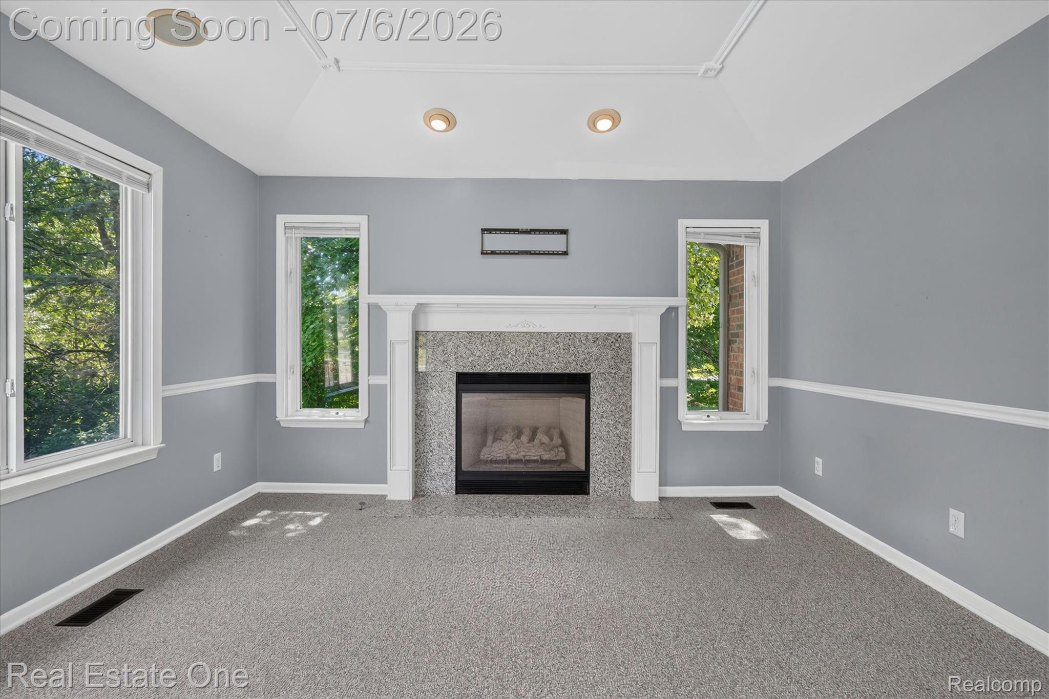 9610 Forest Ridge Drive Clarkston, MI 48348 - Photo 20 of 77 This warm family room offers an expansive, open layout designed for both relaxing and entertaining. A stunning gas fireplace with a classic white mantel serves as the focal point, while soaring vaulted ceilings create an airy sense of space. Large windows fill the room with abundant natural light and showcase beautiful views of the private, wooded backyard. Soft neutral tones and plush carpeting add warmth and comfort, and the seamless connection to the kitchen and breakfast nook.