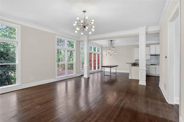 a view of an empty room with wooden floor and a large window