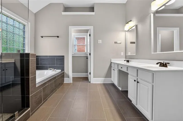 a bathroom with a double vanity sink a mirror and a bathtub