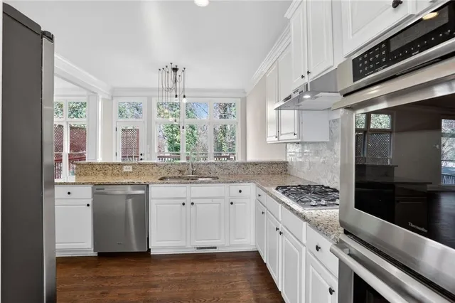 a kitchen with granite countertop stainless steel appliances a sink stove and cabinets