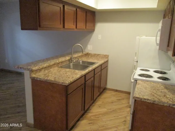 a kitchen with a sink a stove top oven and wooden floor
