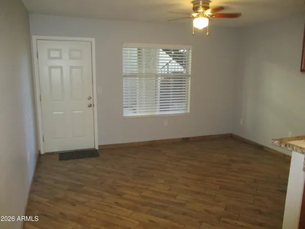 a view of an empty room with wooden floor and a window