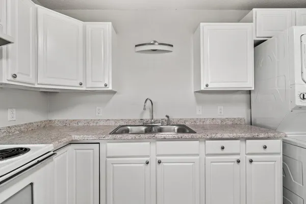 a kitchen with granite countertop white cabinets and a sink